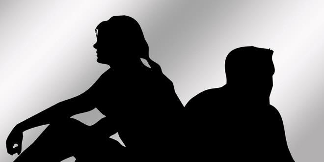 Sort hvitt bilde med to personer som sitter med ryggen mot hverandre