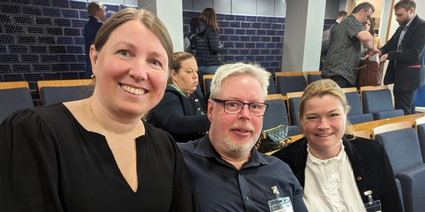 Tre personer i en konferansesal