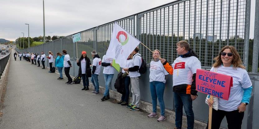 Foto: Mange mennesker i streik med flagg og bannere på ei bru