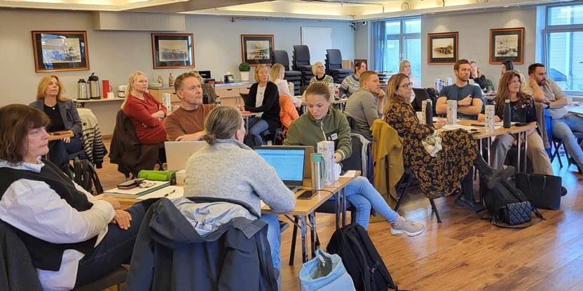 Tilhørere sitter rundt småbord. Foto