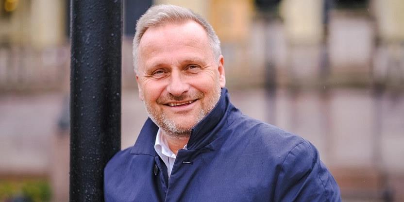 Portrettbilde av en smilende Klemet Rønning-Aaby som står ute med jakke på. Diffus bakgrunn.