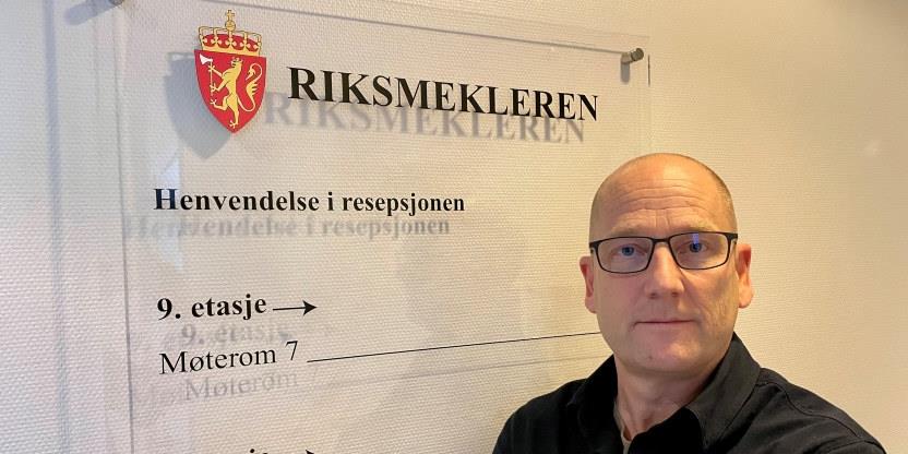 Steffen Handal hos Riksmekleren foran et skilt med skfiten "RIKSMEKLEREN". Foto: Marius G. Vik/Utdanningsforbundet